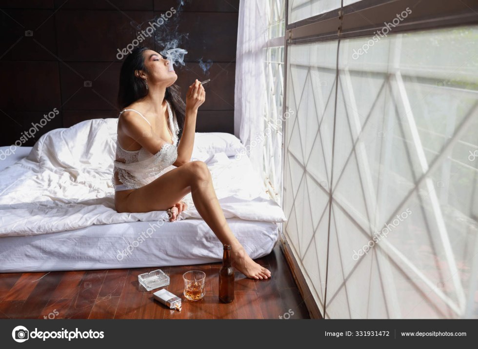 The woman smokes in bed