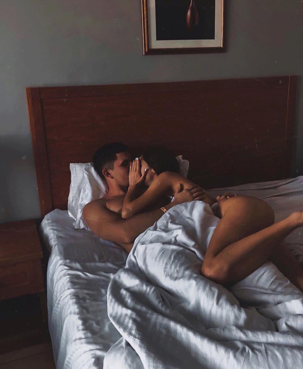 The guy caresses the girl in bed