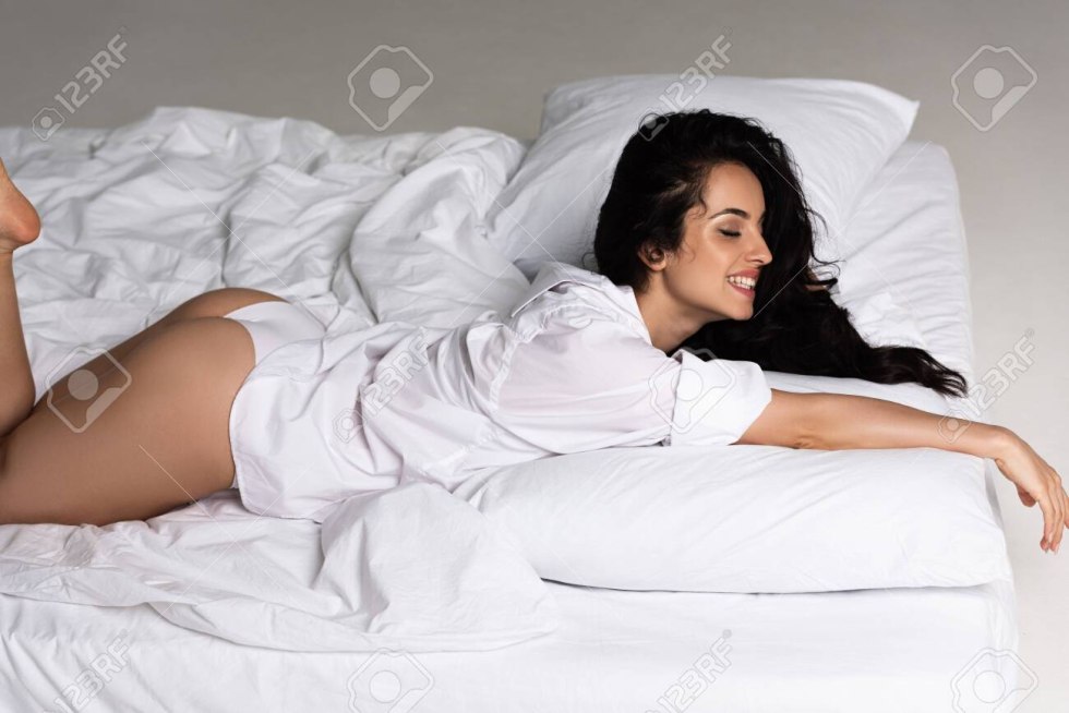 Meghan Markle in a white shirt on the bed