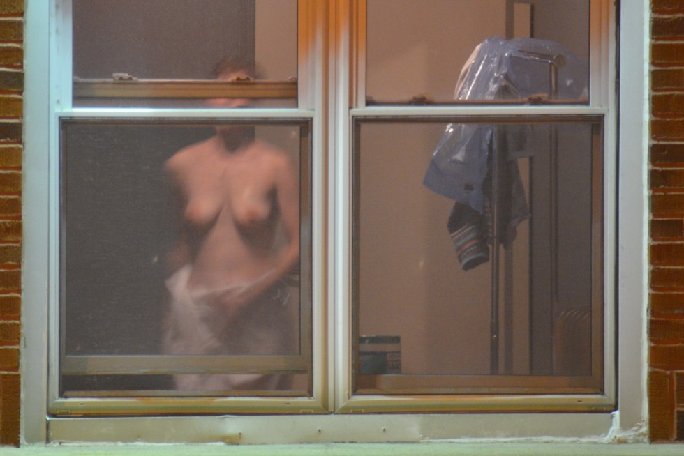 The girl undresses in the window