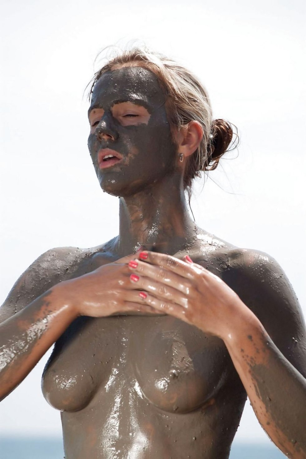 Naked women lying around in mud
