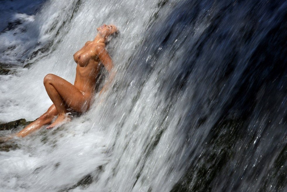 Woman under the nude waterfall